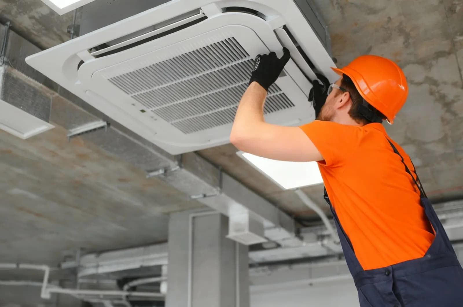Technician servicing a ceiling-mounted air-conditioning unit