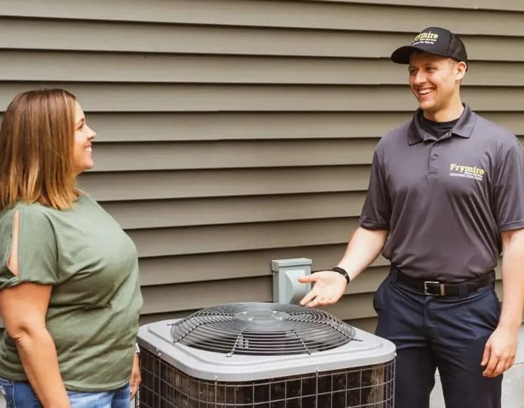 Homeowner discussing a home-comfort service with an engineer beside an outdoor unit