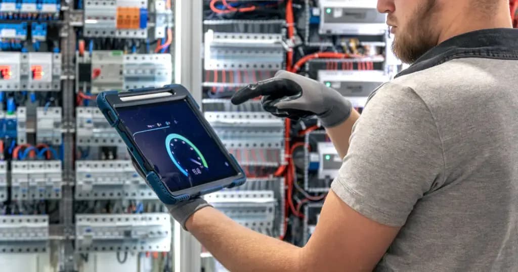Electrician reviewing a switchboard with a digital tablet