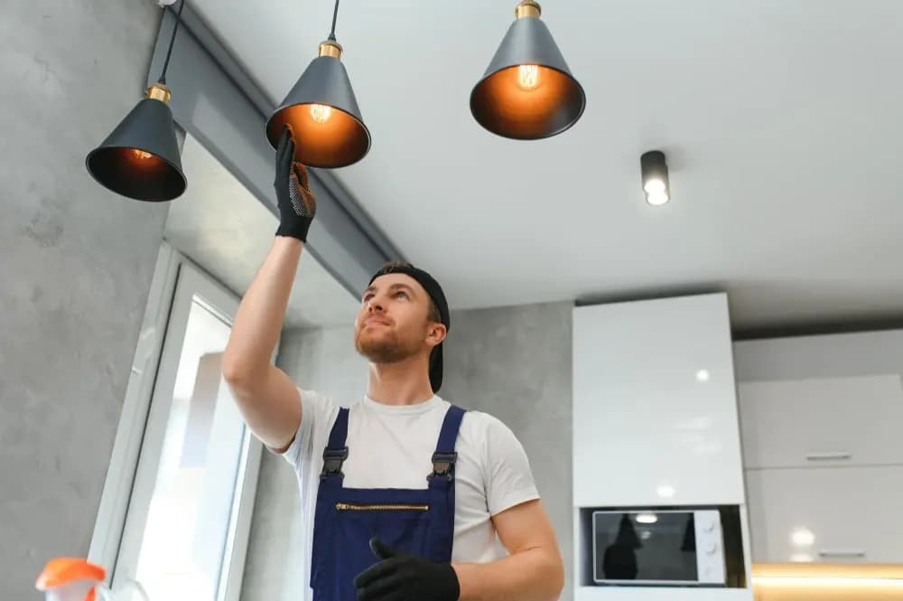 Electrician fitting pendant lighting in a kitchen