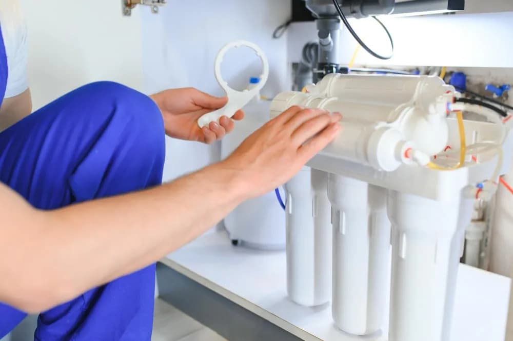 Technician checking a multi-stage water-treatment unit and its connections