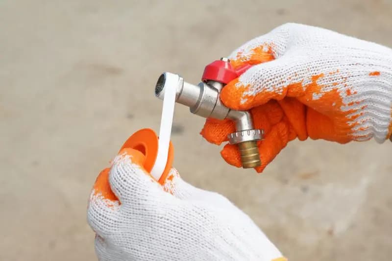 Plumber applying sealant to a pipe fitting for an emergency plumbing route in Surbiton