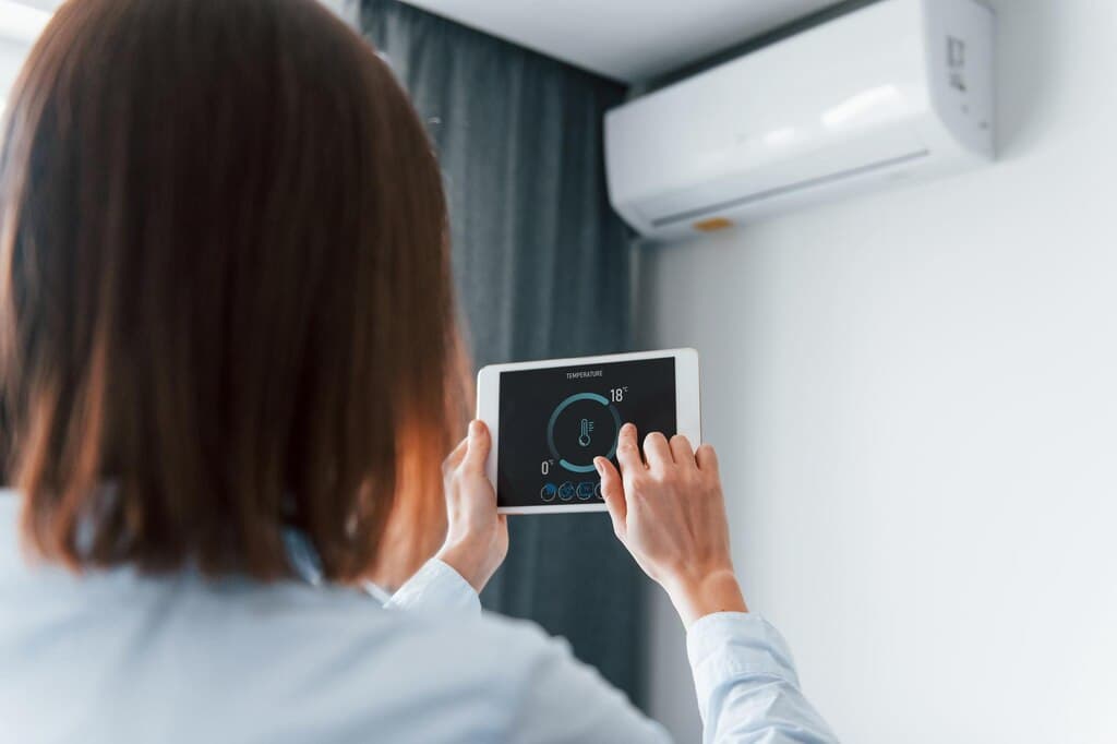 Homeowner using a smart control beside a wall-mounted air conditioner